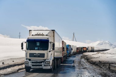 Karla kaplı dağlarda bir kamyon kuyruğu geçidin açılmasını bekliyor. Malların zor hava koşullarında nakliyesi. Bu yüzden paketin gecikti. Gudauri, Gürcistan - 04.08.2021