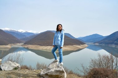 Bir kız, Gürcistan 'da seyahat ederken Zhinvali rezervuarının arka planına karşı poz veriyor. İnanılmaz doğal manzara..