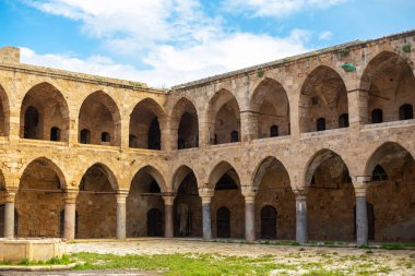 Medieval square building with a courtyard and many arches.