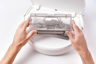 Evi temizledikten sonra robot elektrik süpürgesinden şeffaf toz kabını çıkar. Konteynır tamamen tozla kaplanmış..