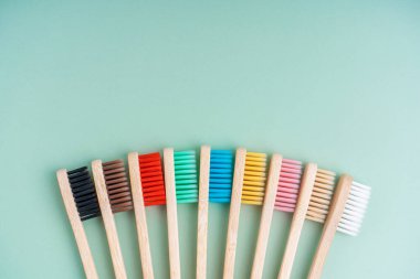 Açık yeşil arka planda bambu ağacından yapılmış çevre dostu antibakteriyel diş fırçaları. Çevresel bakım eğilimleri.