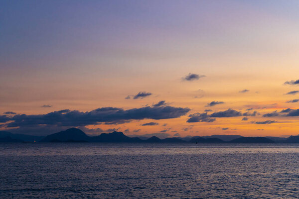 Wonderful sunset landscape on the seashore, colors of the sunset sky and silhouette of island in the water. incredible tropical sunset.