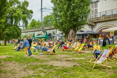 İnsanlar Berlin 'deki bir şehir parkında yeşil çimlerde oturan küçük gruplar halinde dinleniyorlar. Berlin, Almanya - 05.17.2019