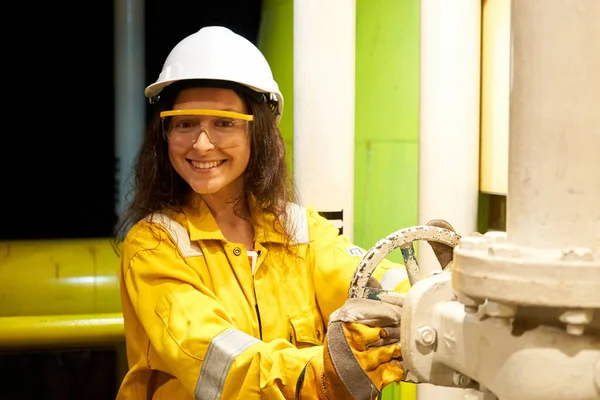 Installation showing the process of drilling an oil well. Woman in worker suit on site.