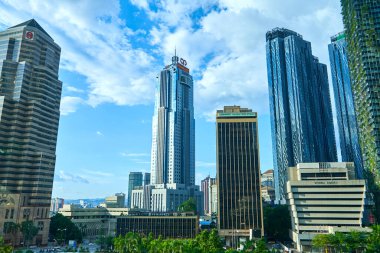 Şehir merkezindeki modern şehir gökdelenine yeşil ağaçlar dikilmiş. Beton ve cam arasındaki yeşillik. Kuala Lumpur, Malezya - 03.14.2020