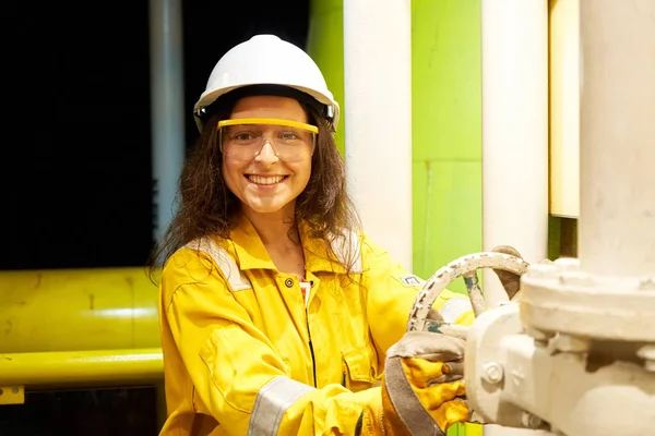 Installation showing the process of drilling an oil well. Woman in worker suit on site.