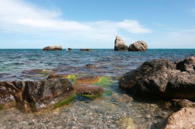Suda büyük taşları olan kayalık bir sahil..
