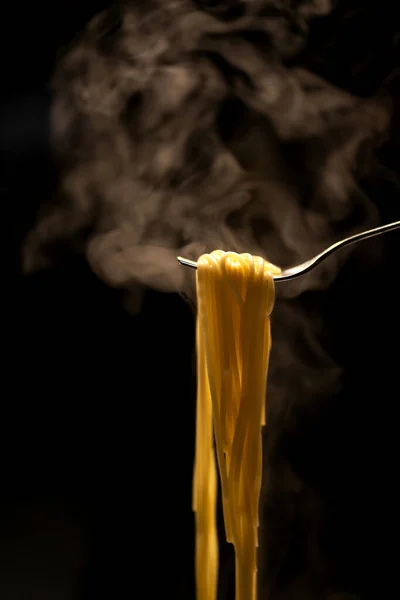 黒を基調としたフォークにかけられた熱々の蒸しスパゲティ — ストック写真