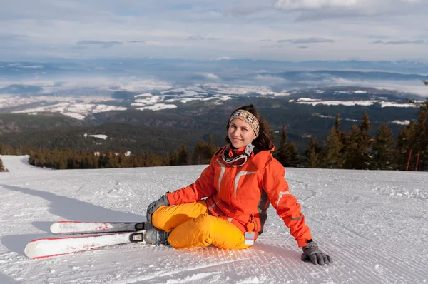 Junge Skifahrerin sitzt auf Schneehügel — Stockfoto