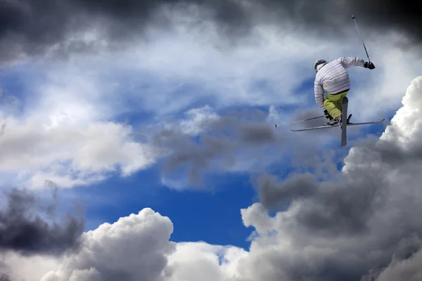 Freestyle ski jumper with crossed skis against cloudy sky — Stock Photo, Image