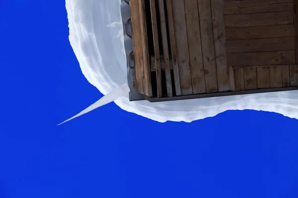 Amoncellement de neige et gros glaçon sur toit en bois — Photo