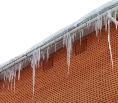 Snow-covered roof with icicles on white background clipart