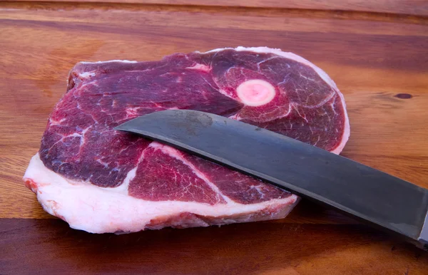 Raw meat with knife on kitchen board — Stock Photo, Image