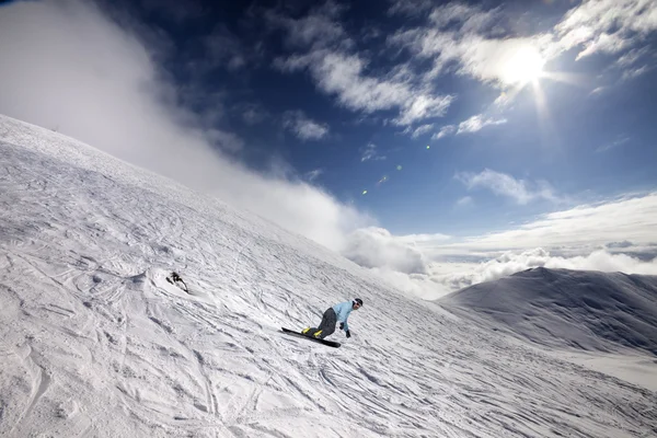 Snowboarder op off-piste ski helling en blauwe hemel met zon — Stockfoto