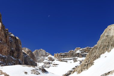moon ile Bulutsuz mavi gökyüzü ve karlı kaya