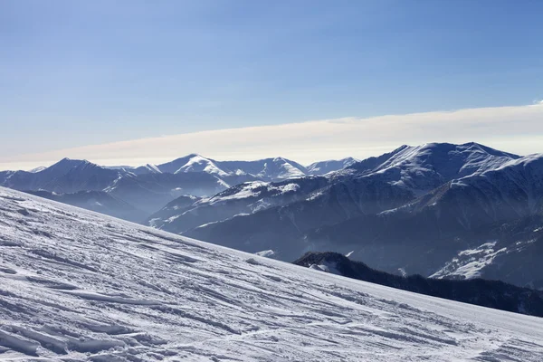 Pista de esquí con el rastro de esquí, snowboard y montañas en neblina —  Fotos de Stock
