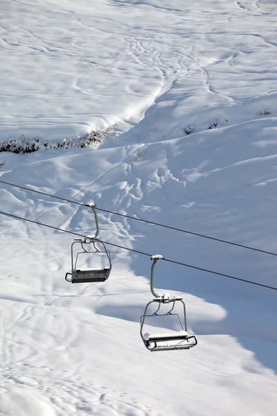 Twee-stoeltjeslift met sneeuwjacht en off-piste helling in de ochtend zon — Stockfoto