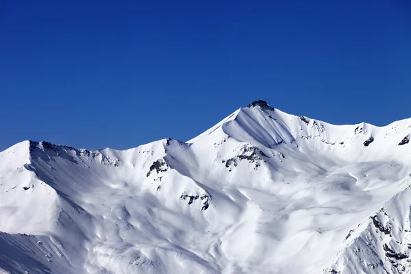 Trasami snowy pochylają i błękitne niebo jasne — Zdjęcie stockowe