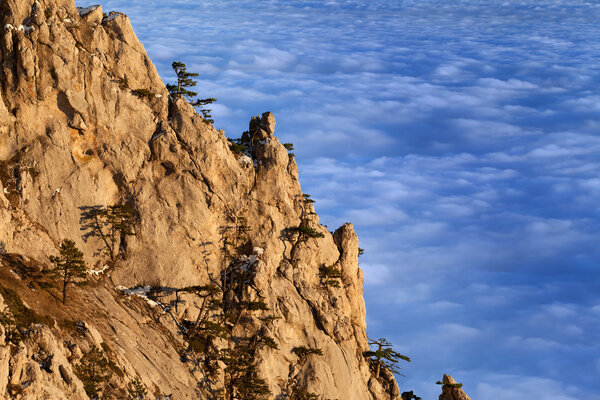 Sunlit cliffs and sea in clouds at evening