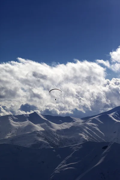 Winter mountain in evening and silhouette of parachutist — Stock Photo, Image