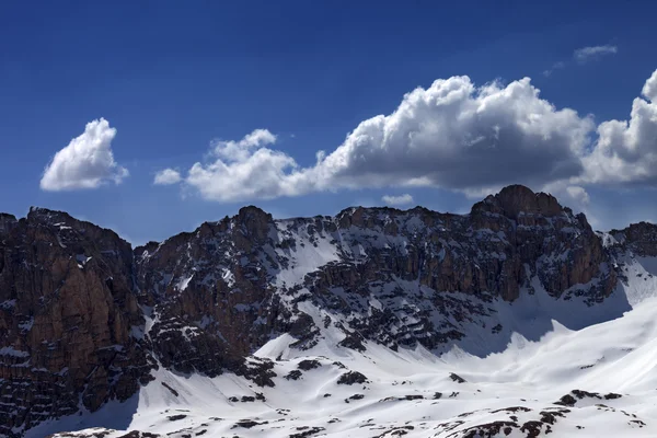 Karlı kayalar ve mavi gökyüzü güneşli bir bahar günü bulut ile — Stok fotoğraf