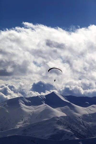 Winter mountains in evening and silhouette of paraglider — Stock Photo, Image