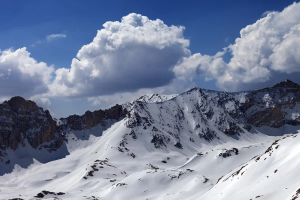 Montañas cubiertas de nieve y un cielo azul con nubes en el día del sol —  Fotos de Stock