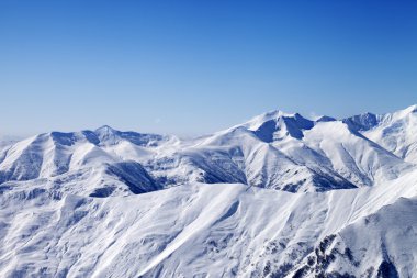 Snowy winter mountains and blue sky, view from ski slope clipart