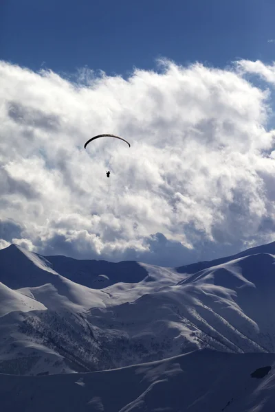 Montagne d'hiver avec des nuages et de la silhouette du parachutiste — Photo