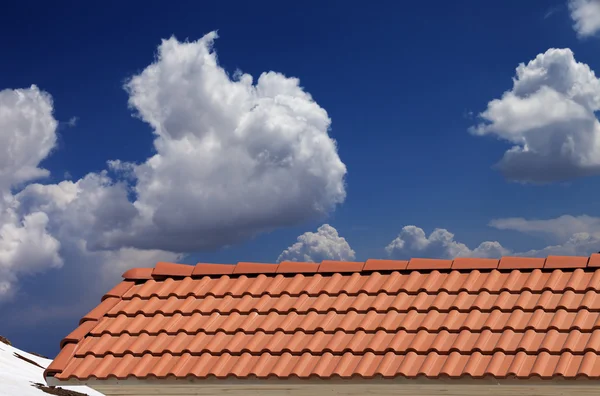 Roof tiles, snowy slope and blue sky with clouds — Stock Photo, Image