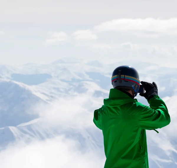 背景には雪の山とカメラで写真を撮るスノーボーダー ジョージア州 グドーリ地方のコーカサス山脈 — ストック写真