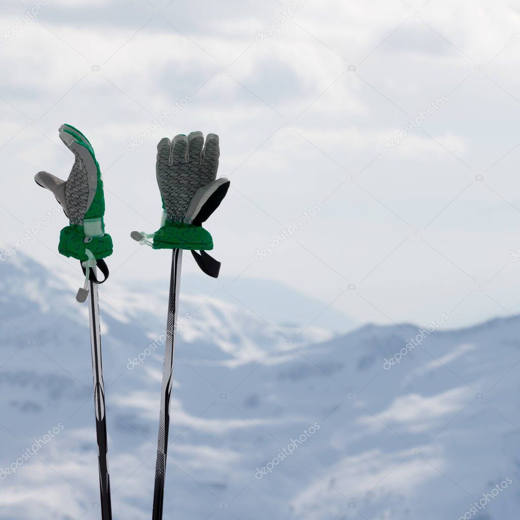 Gloves on ski poles and snowy winter mountain in background. Caucasus Mountains. Georgia, region Gudauri.