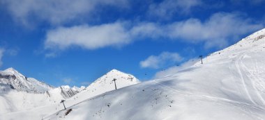 Güneşli bir günde kar pisti dışında panoramik manzara ve kayak merkezinde sandalye kaldırma. Kışın Kafkasya Dağları, Gürcistan, Gudauri bölgesi, Sadzele Dağı.