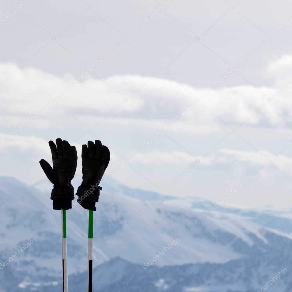 Black men's gloves on ski poles and snowy winter mountains at background. Caucasus Mountains. Georgia, region Gudauri.