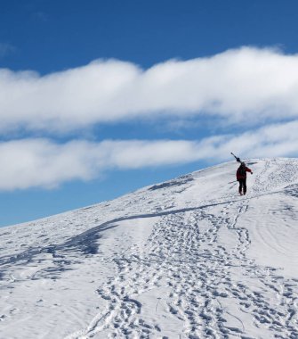 Omzunda kayaklarla kayakçı soğuk güneş gününde karlı dağın zirvesine çıkar. Kışın Kafkasya Dağları, Gürcistan, Gudauri bölgesi, Mt. Kudebi.