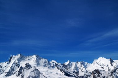 Soğuk güneşli bir günde karlı dağlar ve mavi gökyüzü. Kafkas Dağları, Dombay bölgesi. 