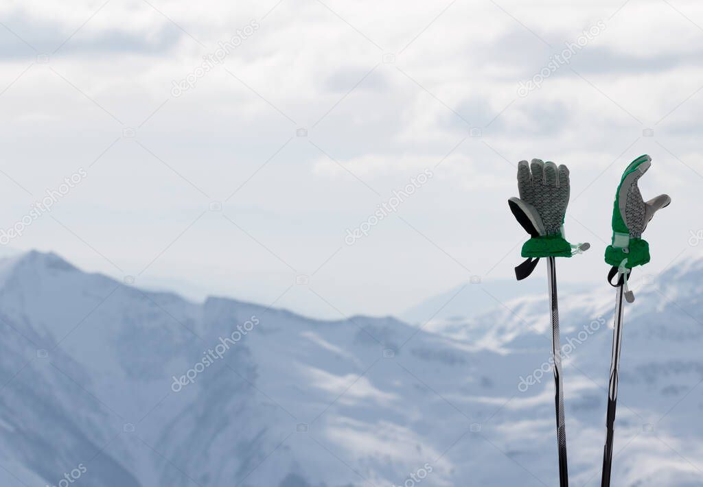 Ladies gloves on ski poles and snowy winter mountain in background. Caucasus Mountains. Georgia, region Gudauri.