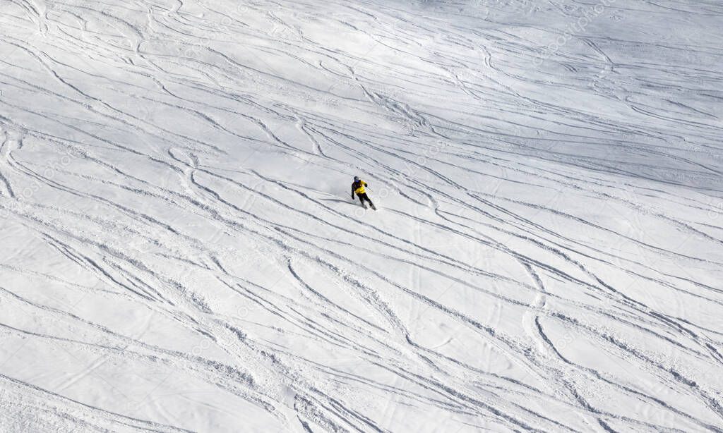 Skier downhill on off-piste snowy ski slope at sun winter day after snowfall. Georgia, region Gudauri. Caucasus Mountains.