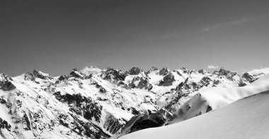 Arka planda Elbrus Dağı ve güneşli soğuk bir günde serbest dolaşmak için buz gibi yamaçta olan siyah beyaz dağ manzarası. Kış mevsiminde Dombay ve Kafkasya Dağları 'ndan manzara.
