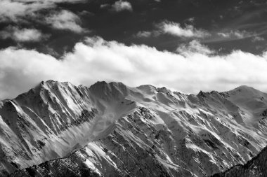 Siyah ve beyaz kar kış dağları ve güneş altında bulutlu gökyüzü. Kafkas Dağları. Gürcistan 'ın Svaneti bölgesi.