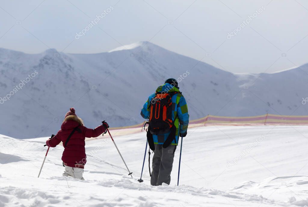 Father and daughter on ski resort after snowfall at sun winter day. Caucasus Mountains, Georgia, region Gudauri.