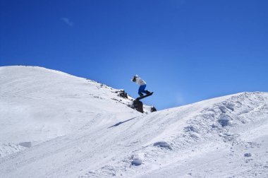 Kar sörfçüsü kış günü kayak merkezindeki arazi parkına atlıyor. Kafkas Dağları, Dombay bölgesi. 