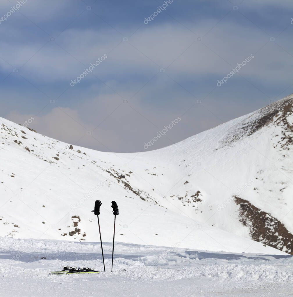 Skiing equipment on snowy ski slope at sunny winter day. Caucasus Mountains, Georgia, region Gudauri.