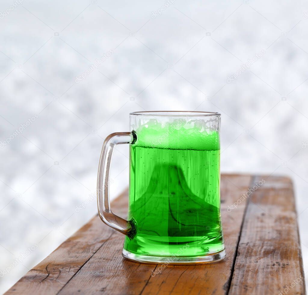 St. Patricks Day. Full fresh cold glass of green beer on wooden bench.