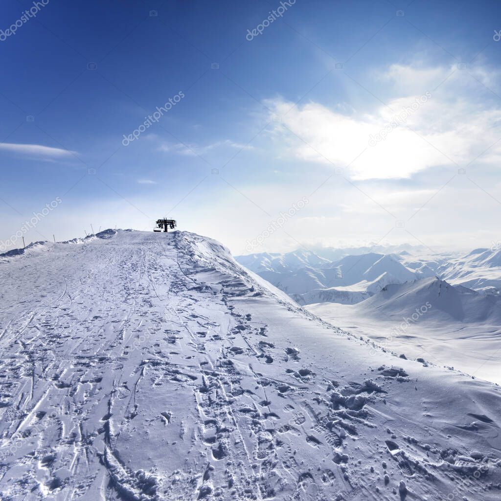 Top station of ropeway and snowy road with footprint in nice sun evening. Caucasus Mountains, Georgia, region Gudauri at winter.