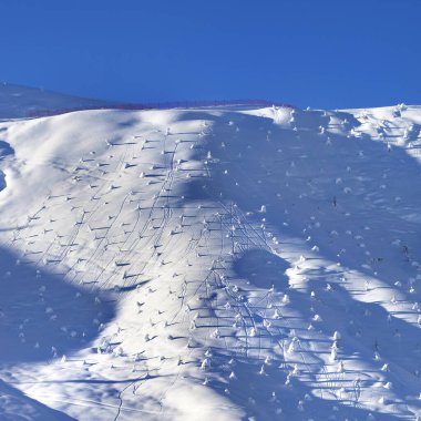 Off-piste snowy slope with little fir after snowfall at early morning. Greater Caucasus in winter, Mount Shahdagh, Azerbaijan.