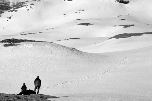 两个徒步旅行者在雪山停下来 黑白色调的风景 — 图库照片