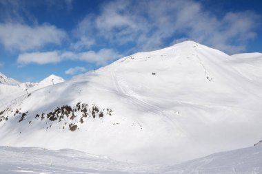 Karlı serbest dolaşım izleri ve güneşli bir günde bulutlu dağlar. Kışın Kafkasya Dağları, Gürcistan, Gudauri bölgesi, Sadzele Dağı manzaralı.