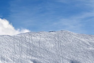 Kar pisti yamaçlarında kayak izleri, snowboard 'lar ve güneşli kış günlerinde bulutları olan güzel gökyüzü var. Kafkasya Dağları, Gürcistan, Gudauri bölgesi.
