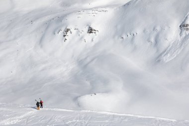 Omzunda kayak izleri, kayak, snowboard ve çığ izleri olan iki kayakçı. Kafkasya Dağları güneş altında soğuk kış günü, Gürcistan, Gudauri bölgesi.